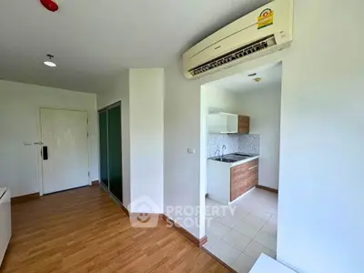 Modern apartment interior with sleek kitchen and wooden flooring, featuring energy-efficient air conditioning.