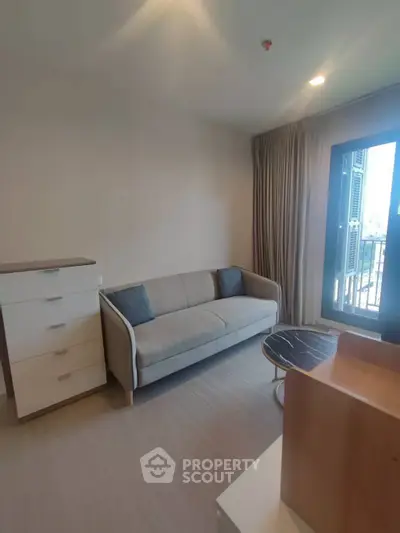 Modern living room with sleek sofa and natural light from balcony.