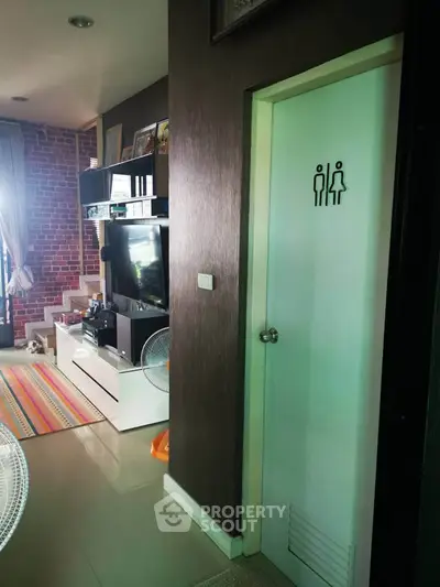 Modern living room with entertainment center and unique restroom door design.