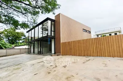 Modern minimalist building with glass facade and wooden fence in serene neighborhood.