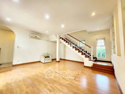Spacious living room with wooden flooring and staircase, perfect for family gatherings.