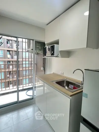 Modern kitchen with sleek cabinets and balcony view in urban apartment