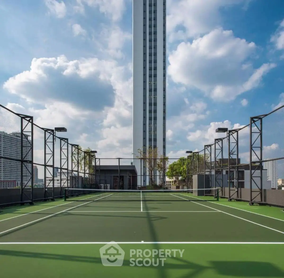 Modern high-rise building with rooftop tennis court and clear blue sky.