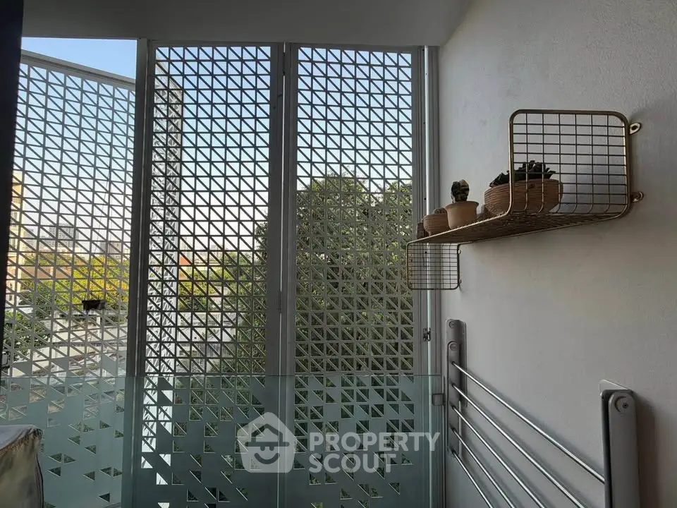 Modern balcony with geometric privacy screen and potted plants, offering a stylish urban view.
