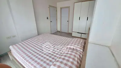 Spacious bedroom with checkered bedding and modern wardrobe in a bright apartment.