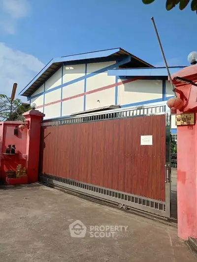 Charming gated property with vibrant red walls and spacious driveway, perfect for privacy and security.