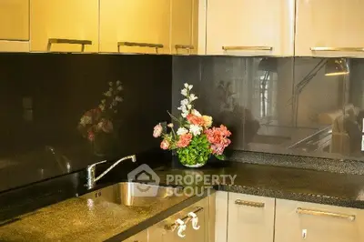 Modern kitchen with sleek cabinets and elegant countertop, featuring a stylish floral arrangement.