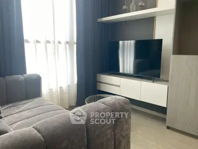 Modern living room with stylish sofa and flat-screen TV, featuring elegant curtains and sleek storage unit.