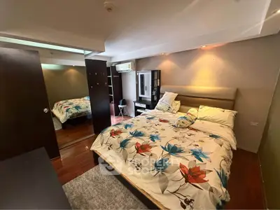 Cozy bedroom with modern decor and ample natural light, featuring a stylish bed and mirrored wardrobe.