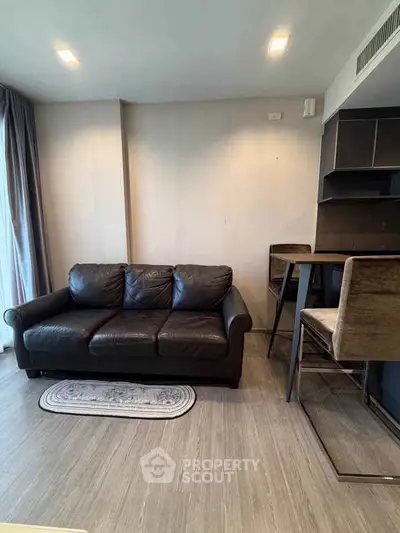 Modern living room with sleek black sofa and stylish bar stools in a cozy apartment setting.