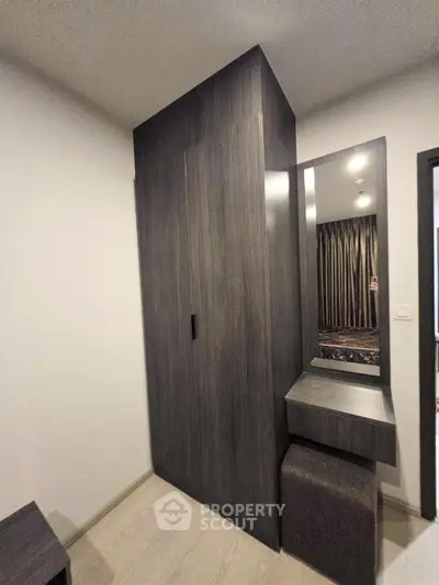 Modern bedroom with sleek dark wood wardrobe and vanity mirror