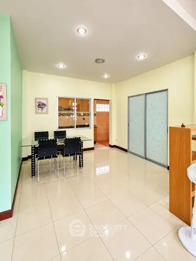 Spacious dining area with modern decor and glass table in a bright, open layout.