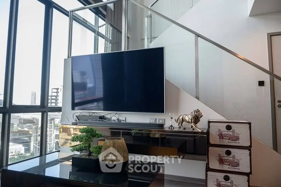 Modern living room with large TV and stylish decor in a high-rise apartment.