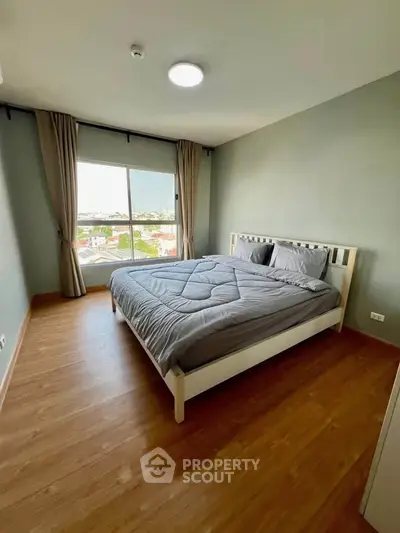 Spacious bedroom with large window and modern decor in a stylish apartment.