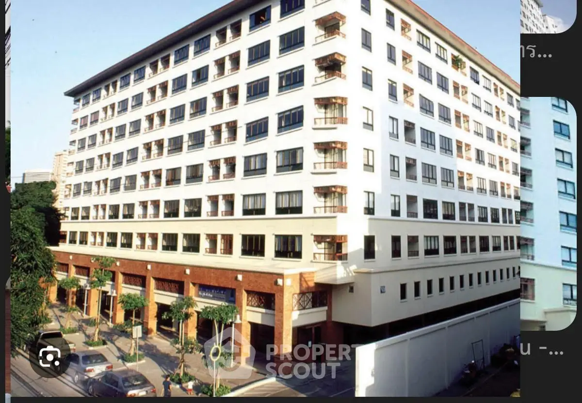 Modern multi-story apartment building with street view and lush greenery.