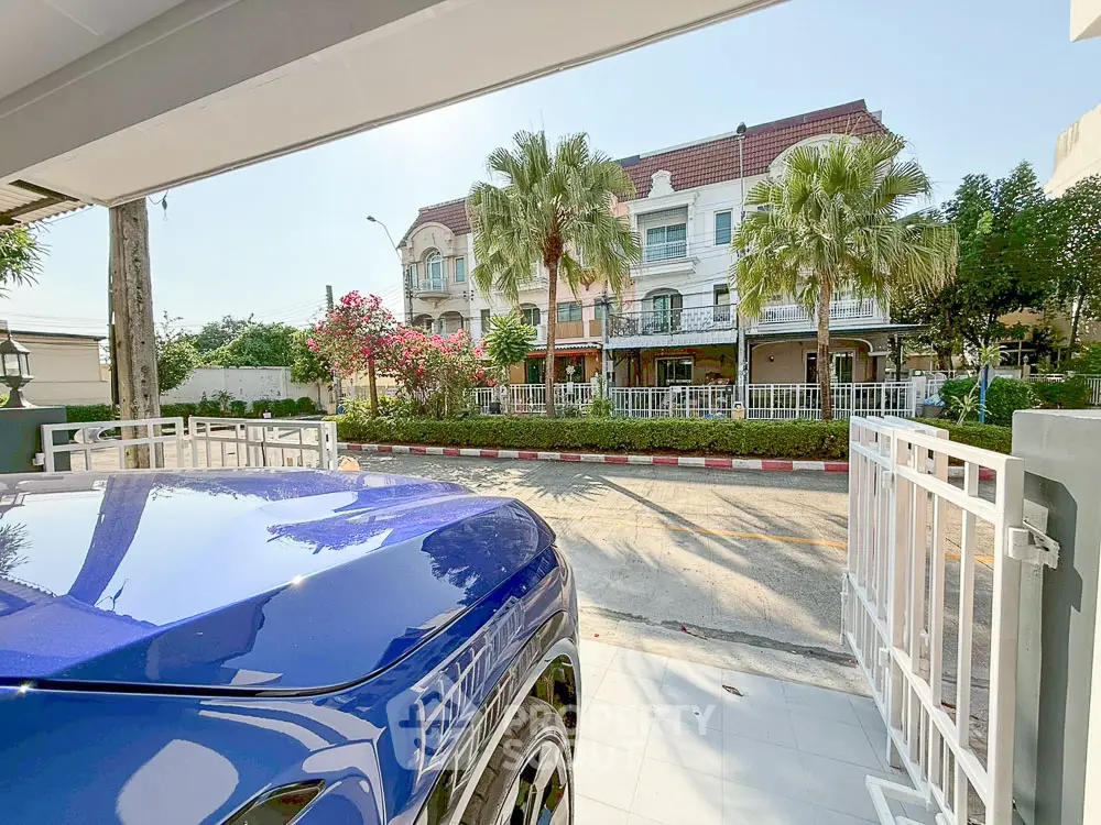 Charming residential street view from a modern home with lush greenery and parked car.