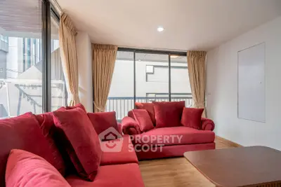 Spacious living room with red sofas and large windows offering natural light