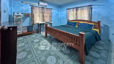 Spacious bedroom with wooden bed frame and tiled flooring, featuring natural light and cozy decor.