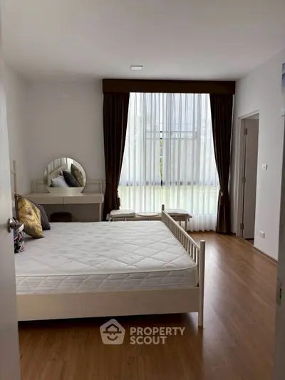 Spacious bedroom with elegant decor and large window for natural light