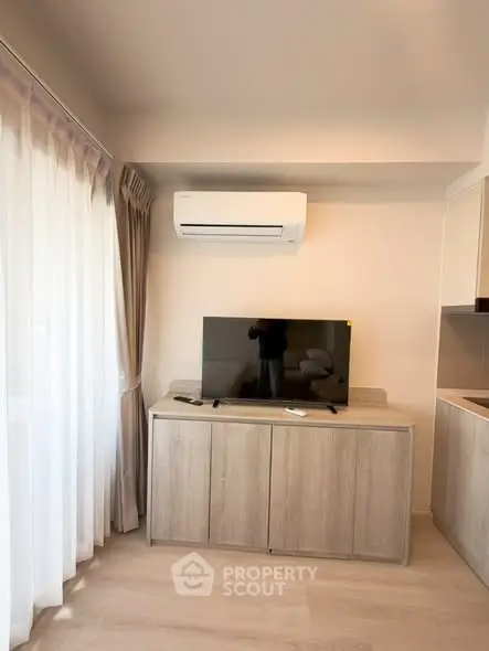 Modern living room with sleek TV stand, air conditioning, and natural light from large window.