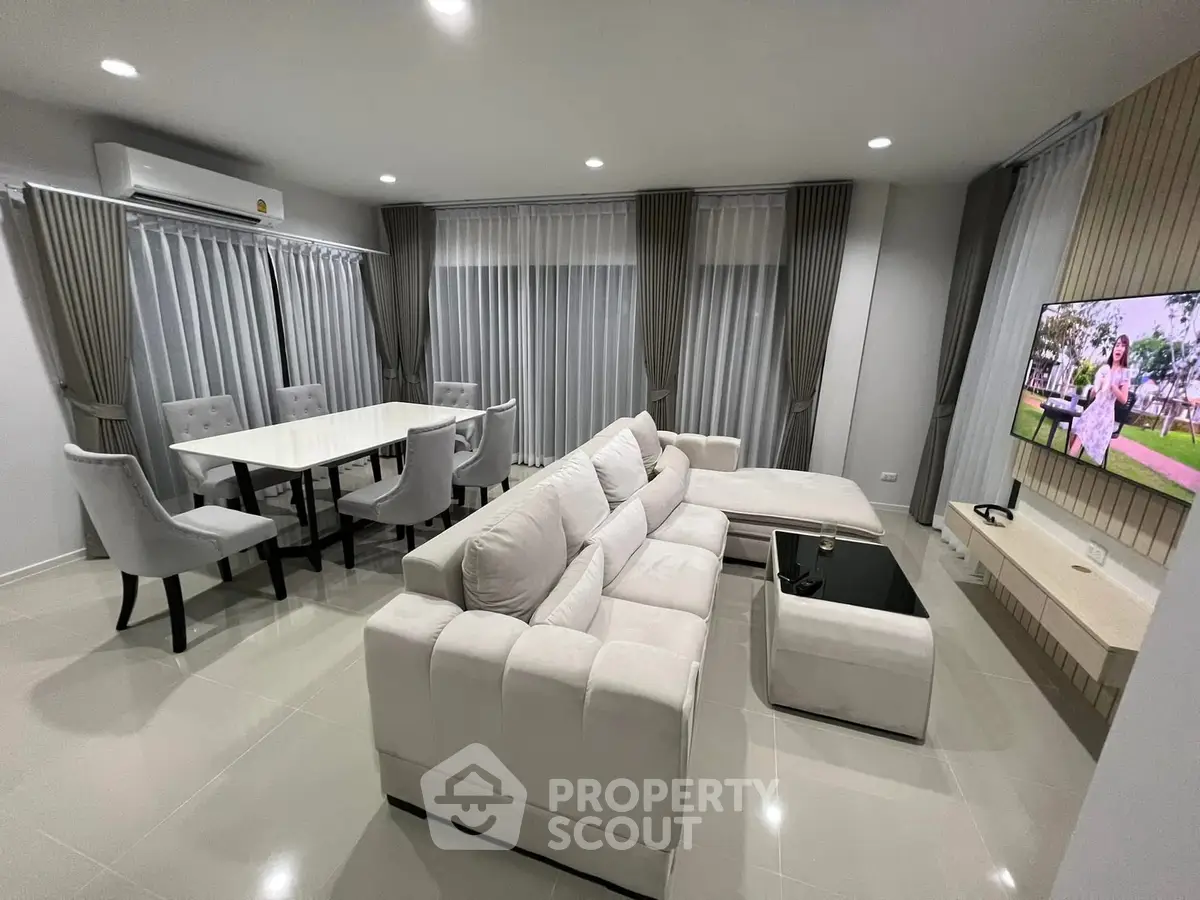 Spacious modern living room with elegant white sofa and dining area, perfect for entertaining.