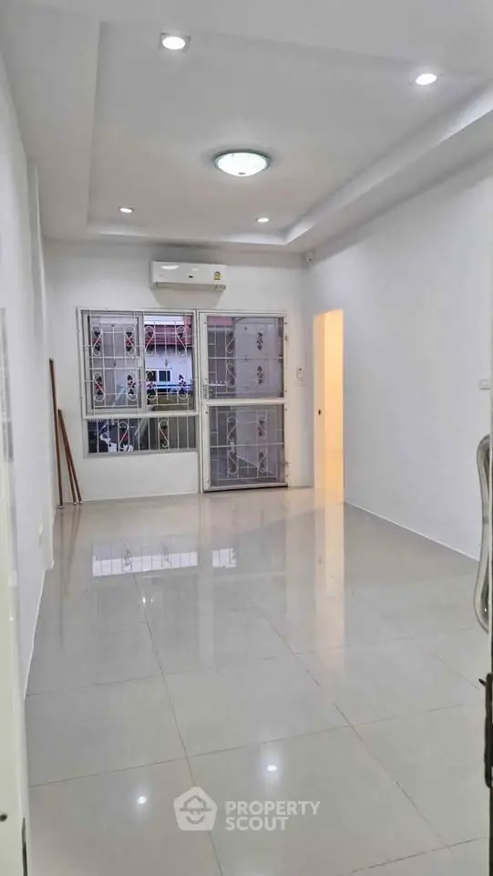 Spacious unfurnished living room with tiled flooring and large windows for natural light.