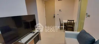 Cozy living room with modern TV setup and dining area in compact apartment.