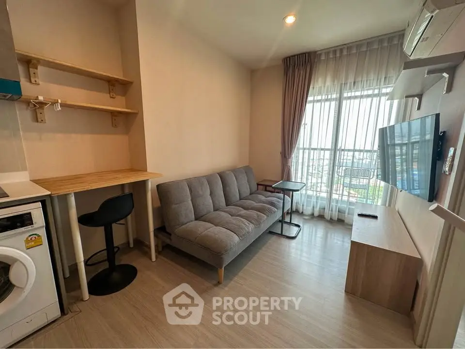 Modern living room with sofa, TV, and washing machine in a bright apartment with city view.