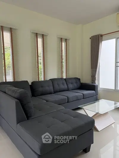 Spacious living room with modern dark gray sectional sofa and glass coffee table.