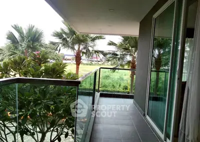Spacious balcony with lush greenery and palm trees view, perfect for relaxation.