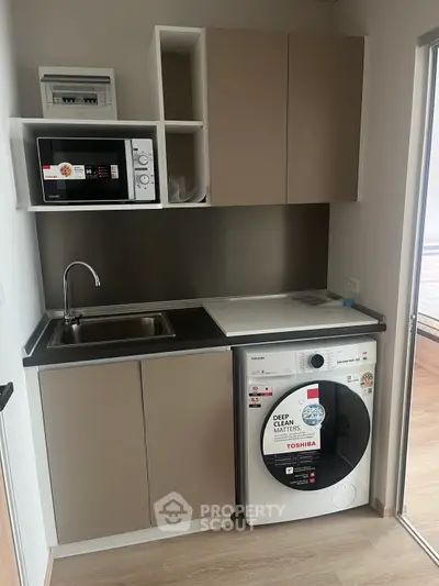 Modern kitchen with washing machine and microwave in compact layout