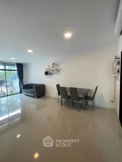 Spacious living room with modern dining area and sleek tile flooring.