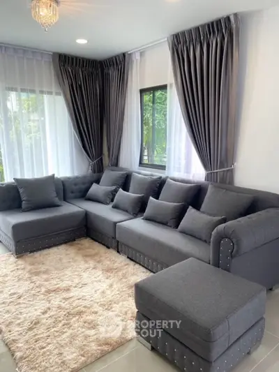 Elegant living room with plush gray sectional sofa and chic curtains, perfect for modern comfort and style.