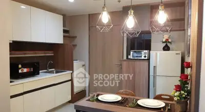 Modern kitchen with stylish lighting, sleek cabinets, and dining area in a cozy apartment.