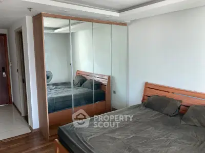 Spacious bedroom with mirrored wardrobe and wooden bed frame in modern apartment.