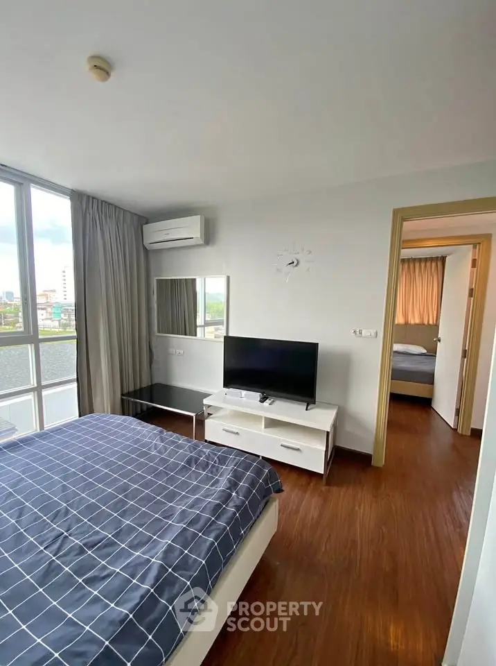 Modern bedroom with large window, stylish decor, and natural light in a high-rise apartment.