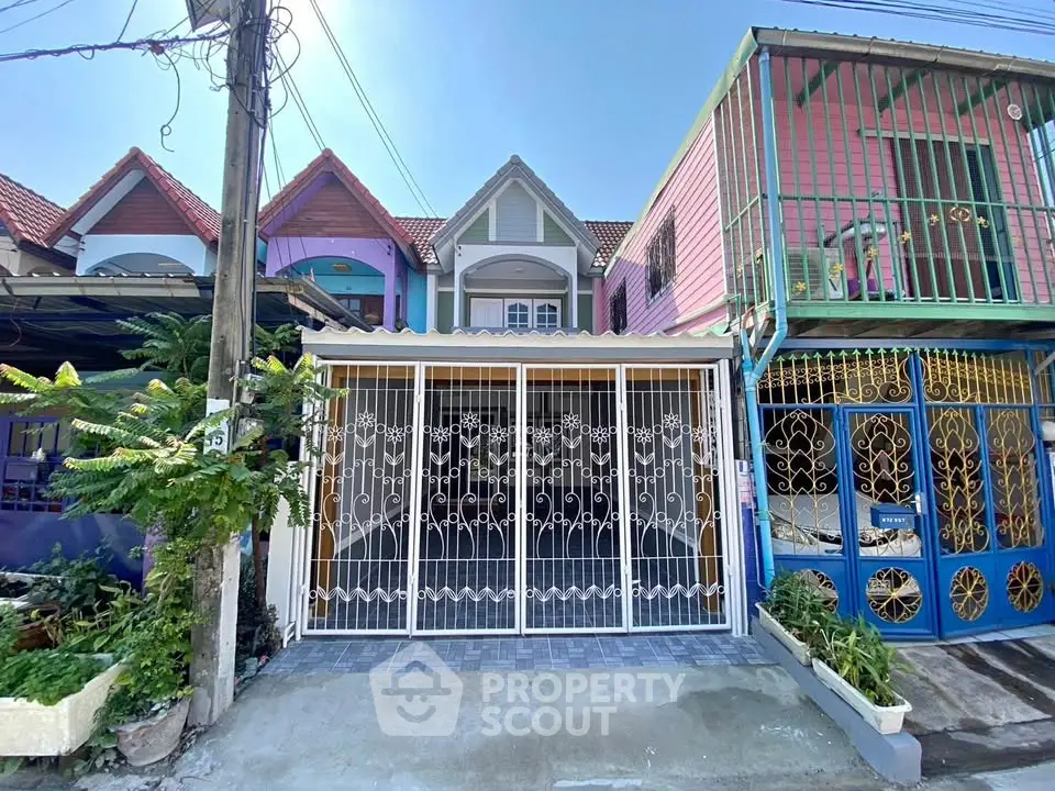 Charming townhouse with colorful facade and secure gated entrance in vibrant neighborhood.
