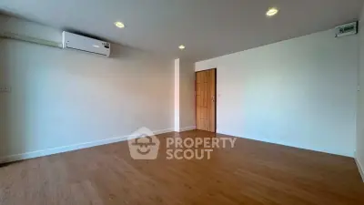 Spacious empty room with wooden flooring and air conditioning, perfect for customization.
