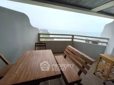 Stunning balcony with ocean view and wooden furniture, perfect for relaxation.
