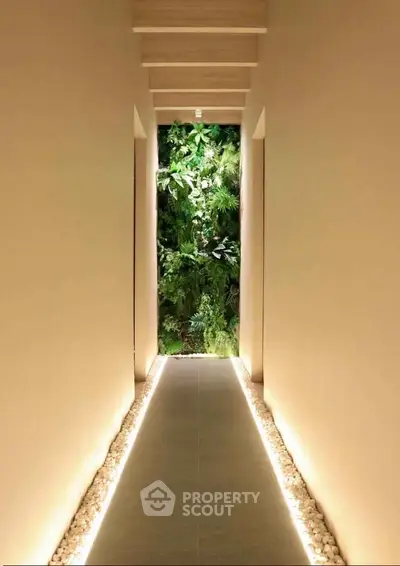 Elegant hallway with modern lighting leading to a lush vertical garden, creating a serene and inviting atmosphere.