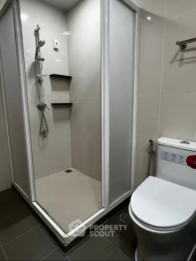 Modern bathroom with sleek shower and toilet in contemporary apartment.