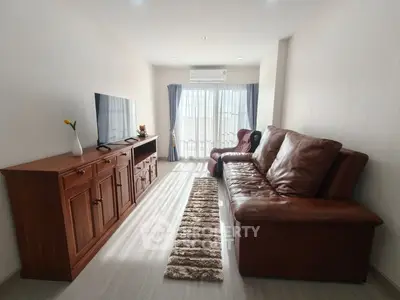 Spacious living room with leather sofa and large TV, perfect for relaxation.