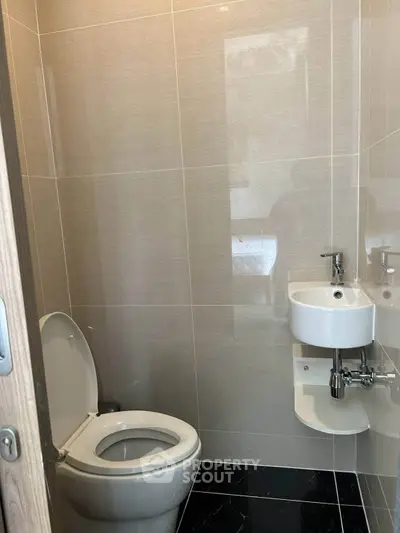 Modern compact bathroom with sleek fixtures and tiled walls.