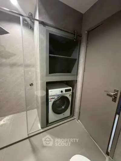 Modern bathroom with built-in washing machine and sleek shower area.