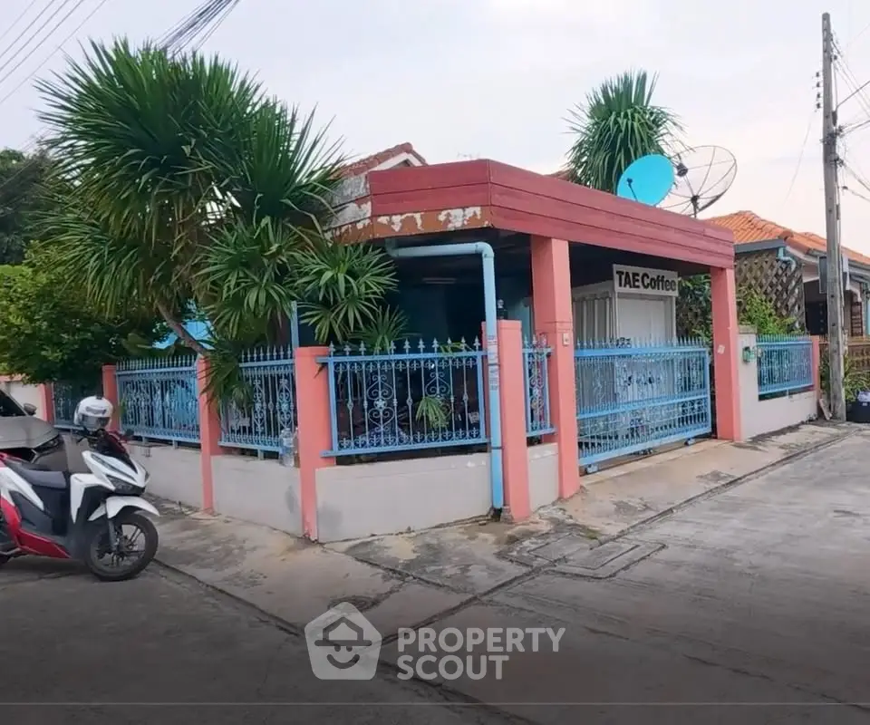Charming corner unit with vibrant exterior and lush greenery, ideal for a cozy cafe or home business.