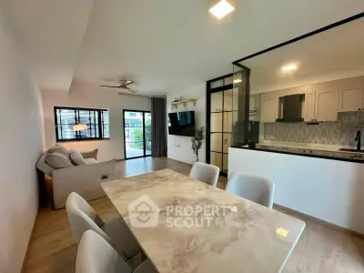 Modern open-concept living and dining area with stylish kitchen and large windows.