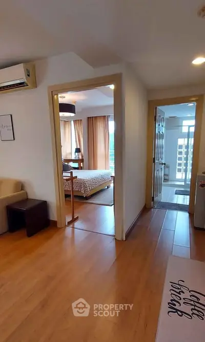 Spacious apartment interior with wooden flooring and modern decor, featuring a cozy bedroom and living area.