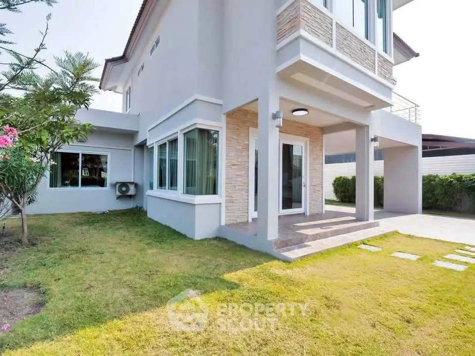 Stunning modern house exterior with lush green lawn and spacious patio area.
