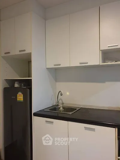 Modern kitchen with sleek cabinetry and compact fridge in minimalist design.