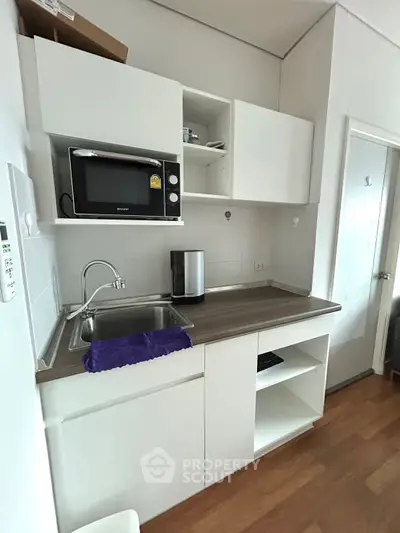 Compact kitchen with modern appliances and sleek cabinetry in a cozy apartment setting.